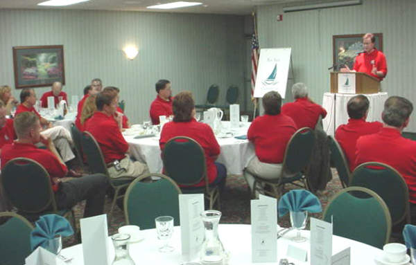 County Executive Tom Hickner addresses the Chamber Business-Government Summit with attendees uniformed in team-building red shirts donated by Joe Liefbroer of S.C. Johnson Co.