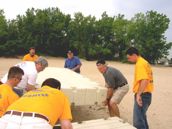 Volunteers including building trades union members and county officials work with Jim Beaudoin of Bluewater Docks, Algonac, right, to heft sections of a floating dock installed Friday at the Bay City State Recreation Area beach.