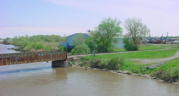 This scene from the Liberty Bridge will soon be history with construction of an earthen berm and planting of evergreens. The old Defoe Shipbuilding structure, foreground, is already gone.