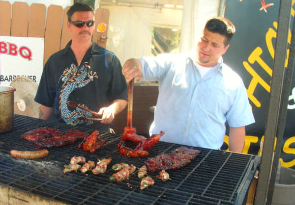 Meats & Mooore Meat Market is grilling out every weekend Friday through Sunday during the summer. Manager Gregg Buzzard (right) displays a tasty selection of meats on the grill.