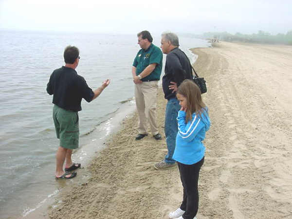 County Commissioner Kim Coonan, DNR official Mike Evanoff, Tom Anderson and Claire Anderson marvel at the clean water and expanse of beach at the Bay City State Recreation Area.