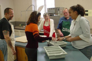 Frank and Gloria Davenport, center, get help from Denny Mayhew, Marci Socia and Cassandra Murphy, right, in preparing Food of Faith meals for the needy.